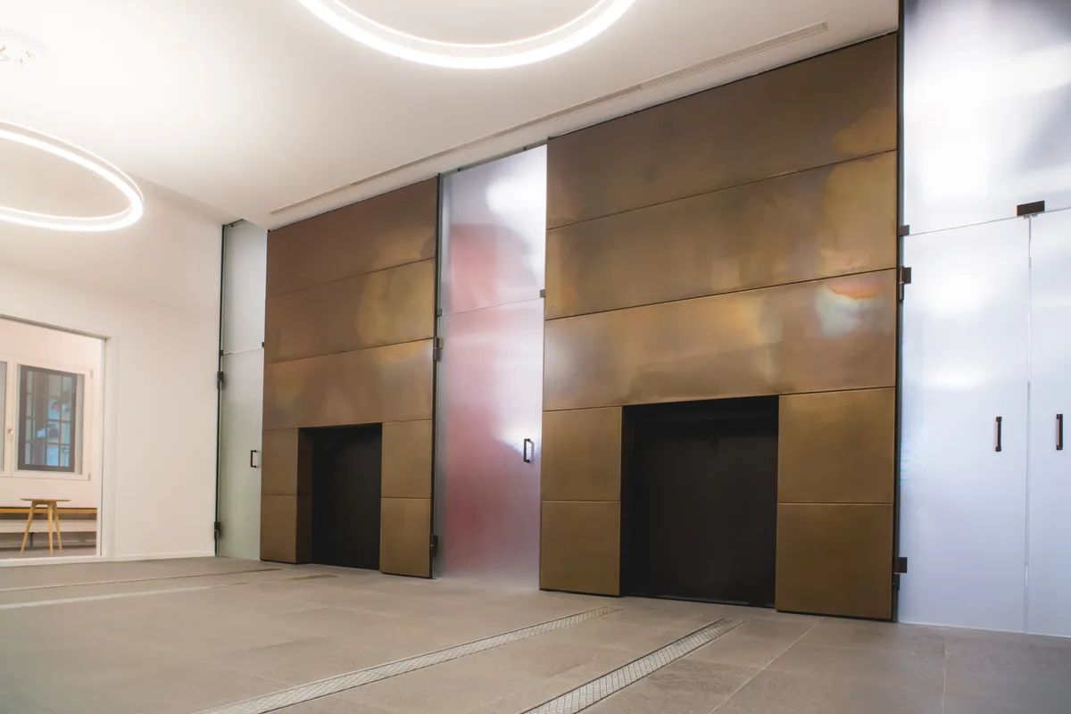Der Energieverbund Rüti Zentrum nutzt auch die Abwärme aus dem Krematorium. Blick ins Krematorium von Rüti. Man sieht einen kargen Raum mit zwei grossen Öffnungen der Einäscherungsöfen in der Wand.